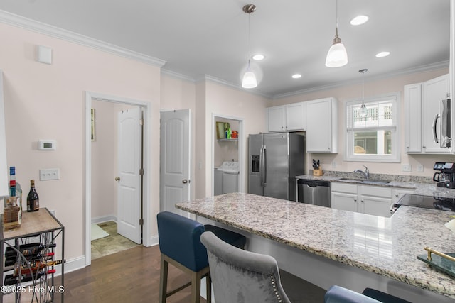kitchen with crown molding, a peninsula, a sink, dark wood finished floors, and appliances with stainless steel finishes