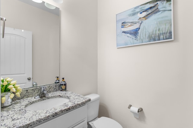 half bath featuring vanity and toilet