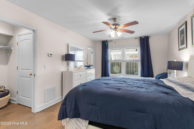 bedroom featuring visible vents, a ceiling fan, baseboards, and wood finished floors