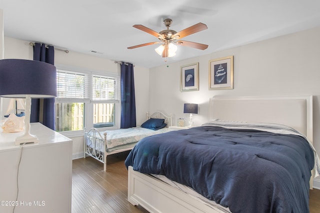 bedroom with ceiling fan, dark wood finished floors, and visible vents