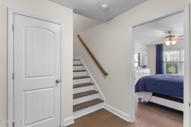 stairs featuring baseboards, a ceiling fan, and wood finished floors