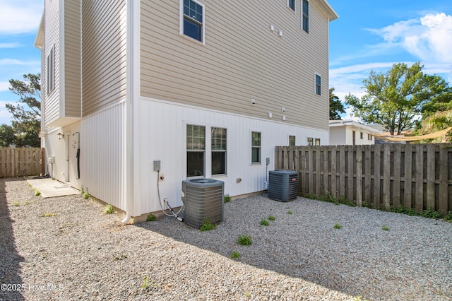 rear view of house featuring fence and central AC unit