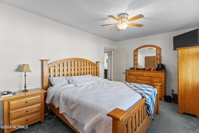 bedroom featuring a textured ceiling, dark colored carpet, and ceiling fan