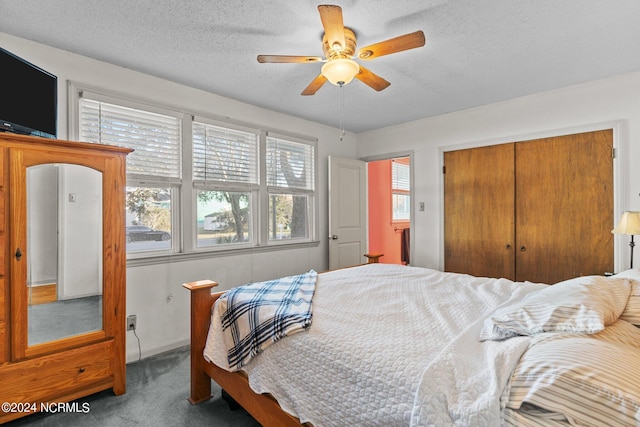 bedroom with a closet, a textured ceiling, dark carpet, and ceiling fan