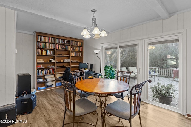 dining area featuring a notable chandelier, beam ceiling, light hardwood / wood-style floors, and a healthy amount of sunlight