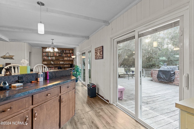 kitchen featuring light wood-type flooring, hanging light fixtures, an inviting chandelier, and beam ceiling