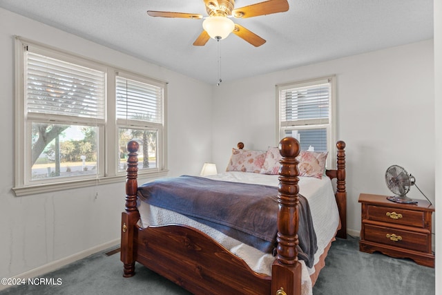 bedroom featuring ceiling fan, dark carpet, and a textured ceiling