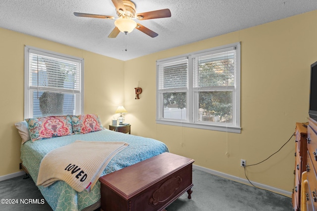 carpeted bedroom with a textured ceiling, ceiling fan, and multiple windows