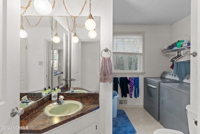 bathroom featuring washing machine and clothes dryer, toilet, vanity, and tile flooring