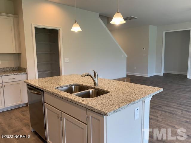 kitchen featuring sink, light stone counters, stainless steel dishwasher, an island with sink, and white cabinets