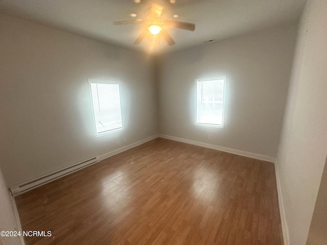 empty room featuring dark hardwood / wood-style flooring, ceiling fan, and a baseboard radiator