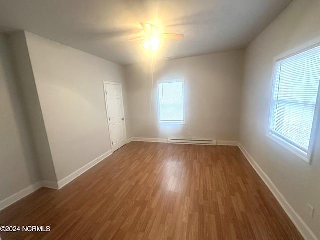 spare room with dark hardwood / wood-style floors, ceiling fan, and a baseboard heating unit