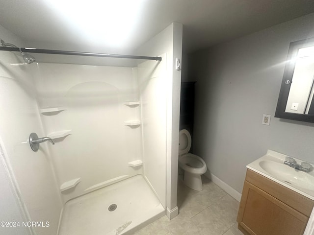 bathroom with a shower, toilet, vanity with extensive cabinet space, and tile flooring