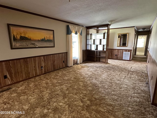 unfurnished living room featuring ornamental molding, a textured ceiling, and carpet floors