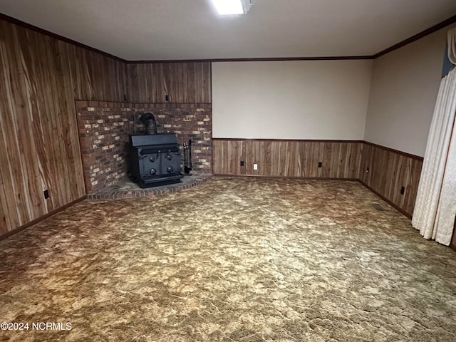 unfurnished living room with crown molding, wood walls, a wood stove, and dark carpet