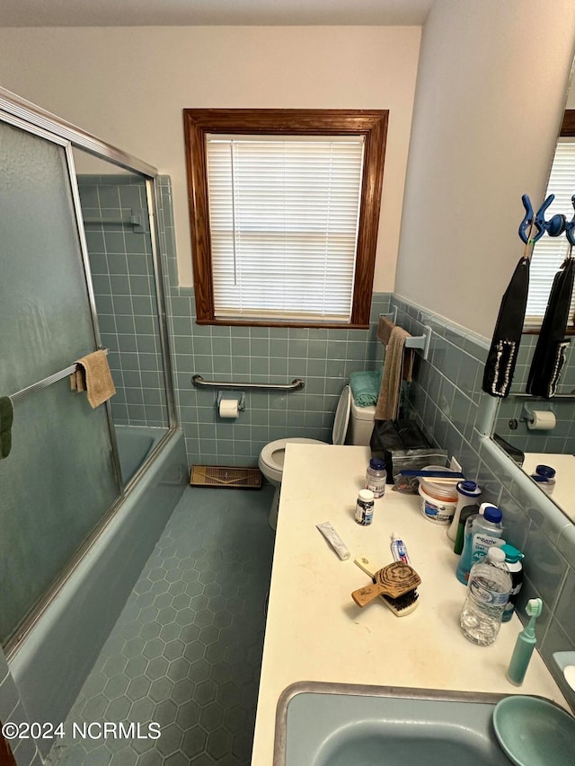 full bathroom featuring tile flooring, tasteful backsplash, enclosed tub / shower combo, toilet, and vanity with extensive cabinet space