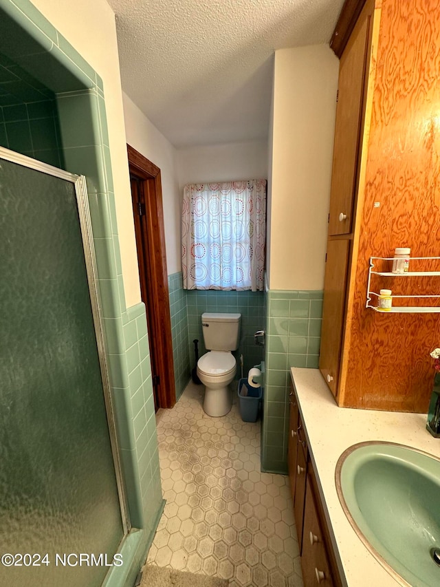 bathroom with vanity, tile walls, tile flooring, a textured ceiling, and toilet