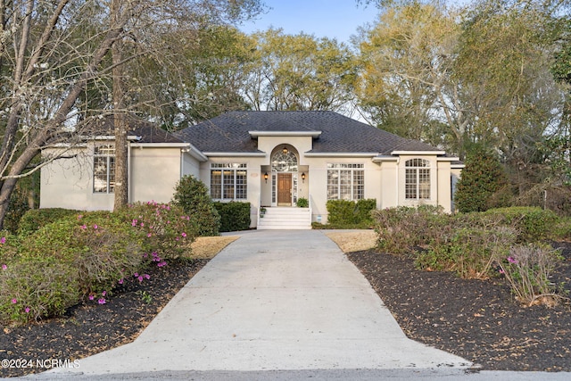 ranch-style home featuring a shingled roof and stucco siding