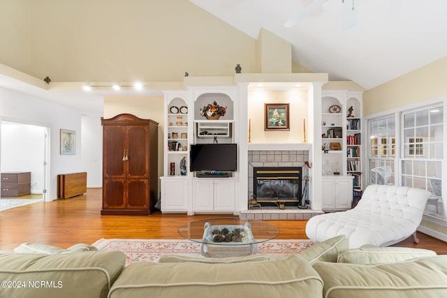 living room featuring high vaulted ceiling, light wood-type flooring, a tile fireplace, and ceiling fan