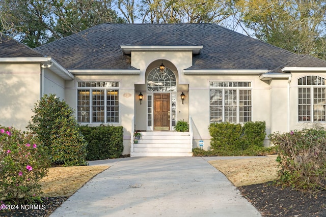 view of front of home featuring a shingled roof and stucco siding