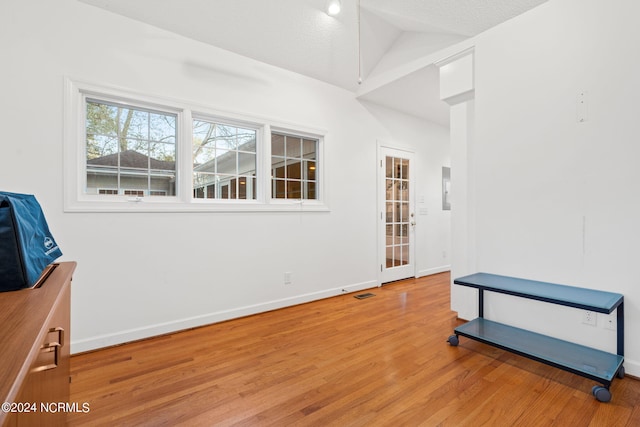 empty room featuring lofted ceiling, a textured ceiling, and wood-type flooring