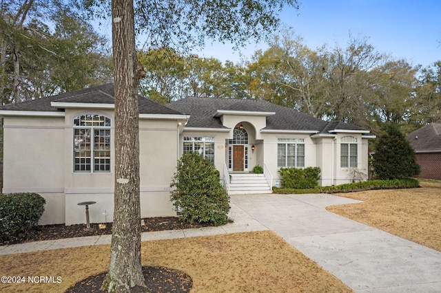 single story home featuring roof with shingles and stucco siding