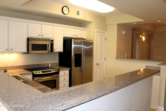 kitchen featuring light stone counters, kitchen peninsula, white cabinetry, and stainless steel appliances