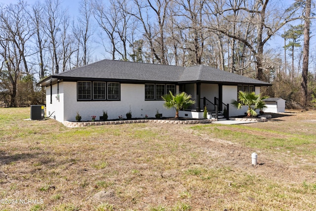 view of front of property with a front yard, a garage, and central air condition unit