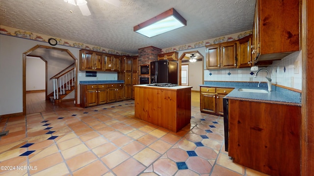 kitchen featuring ceiling fan, backsplash, black appliances, and sink