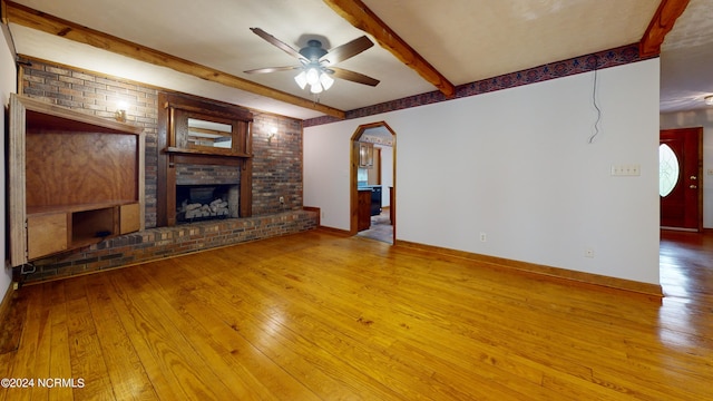 unfurnished living room featuring beam ceiling, a brick fireplace, ceiling fan, and light hardwood / wood-style flooring