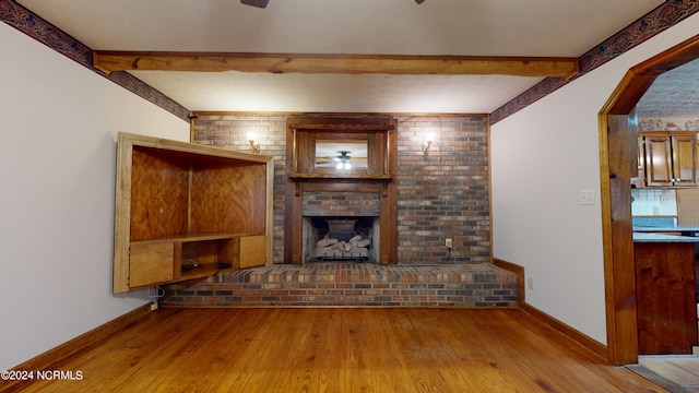 unfurnished living room featuring beam ceiling, wood-type flooring, and a fireplace