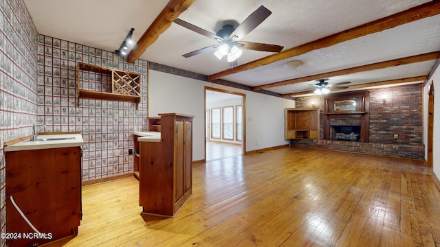 unfurnished living room with beam ceiling, brick wall, and ceiling fan