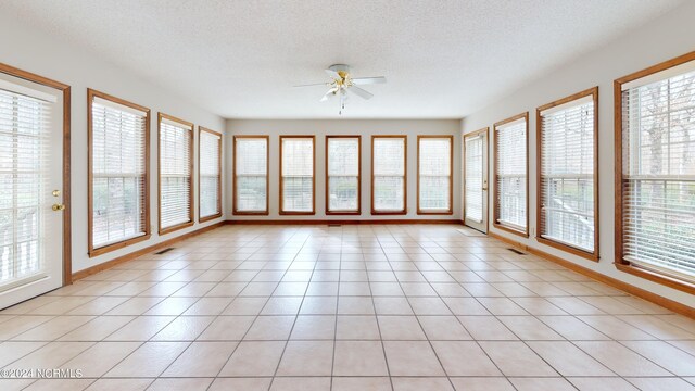 unfurnished sunroom with ceiling fan