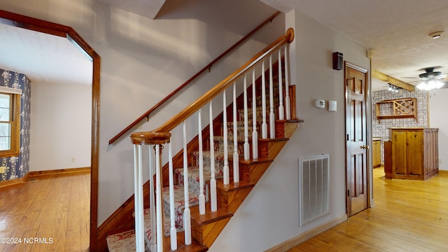 stairs with ceiling fan and light wood-type flooring