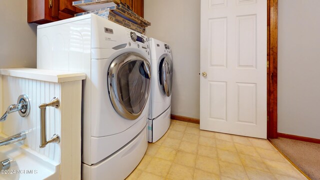 laundry area featuring light tile floors, cabinets, and washer and clothes dryer