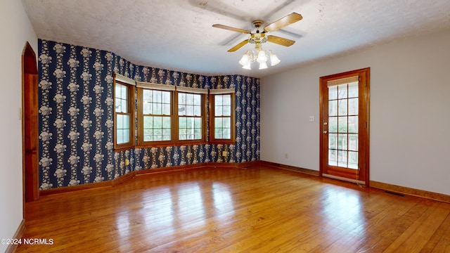 empty room featuring a healthy amount of sunlight, ceiling fan, and light wood-type flooring