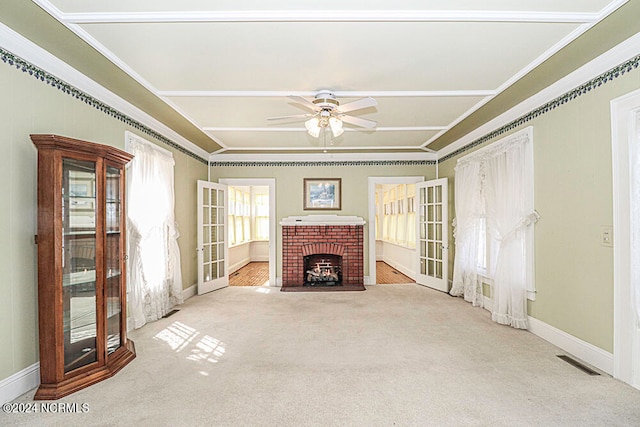 unfurnished living room with crown molding, a brick fireplace, ceiling fan, and light carpet