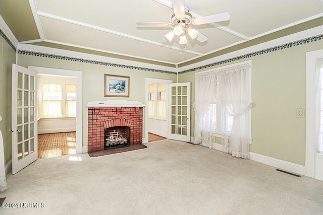 unfurnished living room with light carpet, french doors, crown molding, a fireplace, and ceiling fan