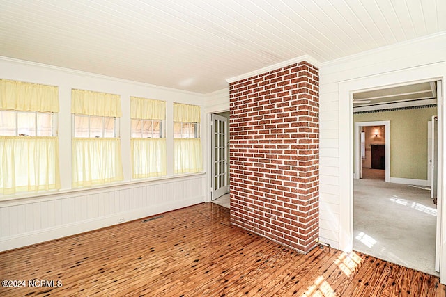 spare room with brick wall, crown molding, and hardwood / wood-style flooring