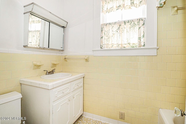 bathroom featuring tile floors, large vanity, toilet, and tile walls