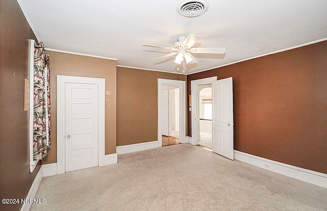 unfurnished bedroom with ceiling fan, crown molding, and light carpet