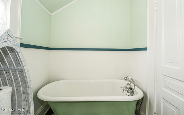 bathroom with a bathing tub, ornamental molding, and vaulted ceiling