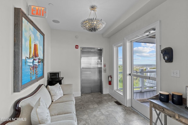 tiled living room with plenty of natural light, a notable chandelier, and elevator