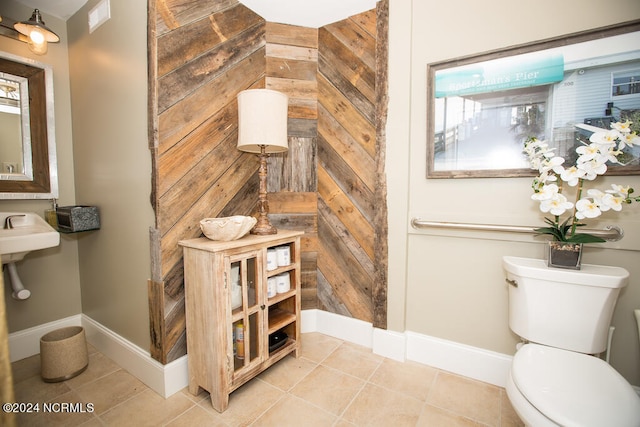 bathroom with toilet, wooden walls, and tile patterned floors