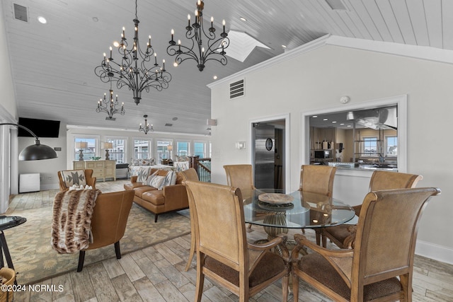 dining room featuring high vaulted ceiling, light hardwood / wood-style flooring, and a chandelier