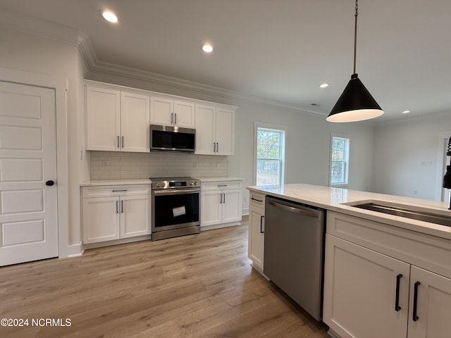 kitchen featuring white cabinets, hanging light fixtures, appliances with stainless steel finishes, and light hardwood / wood-style flooring