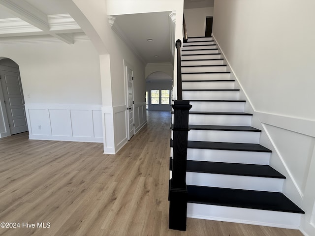 stairway featuring beam ceiling, crown molding, hardwood / wood-style floors, and coffered ceiling