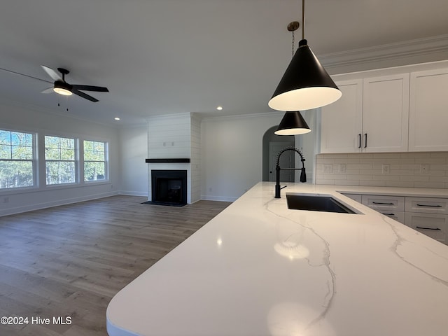 kitchen with white cabinets, sink, light wood-type flooring, tasteful backsplash, and light stone counters