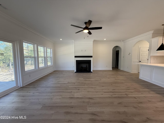 unfurnished living room featuring a large fireplace, light wood-type flooring, and ornamental molding