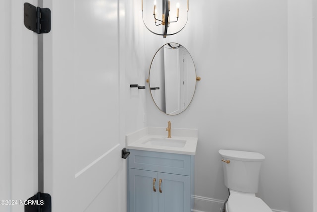 bathroom featuring vanity, toilet, and a notable chandelier